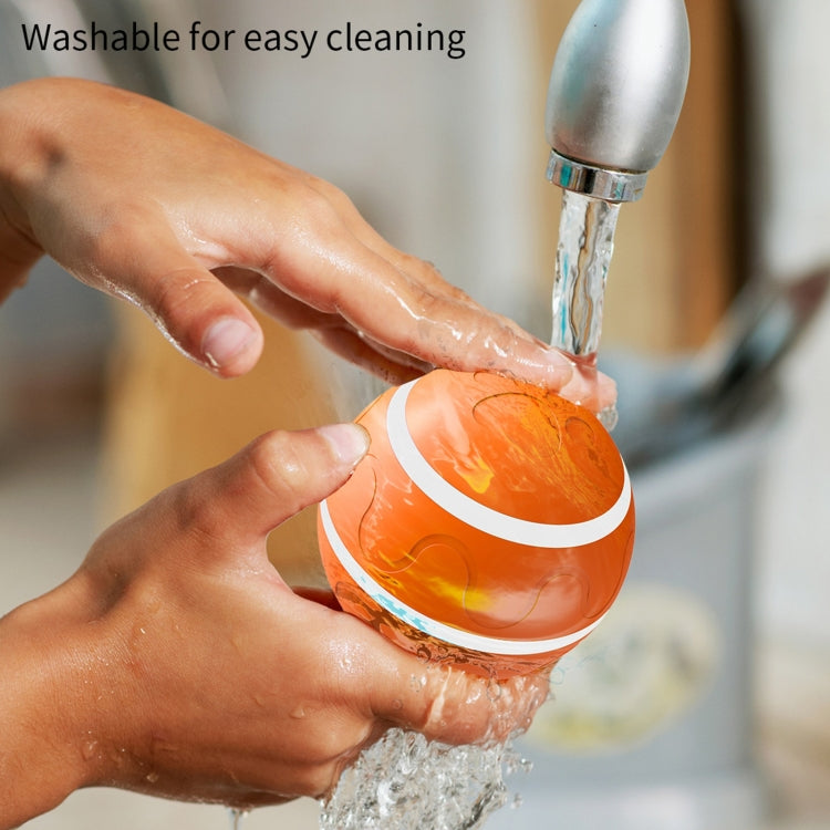 Washable auto pet toy ball being rinsed under running water in hand