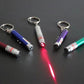 Multiple LED laser pen keychains on a dark surface with a red laser beam spot.