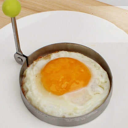 Round omelet mold with green knob handle, holding a fried egg.