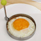 Round frying mold with green knob handle, fried egg centered.