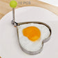 Heart-shaped omelet mold with green knob handle, holding a fried egg.