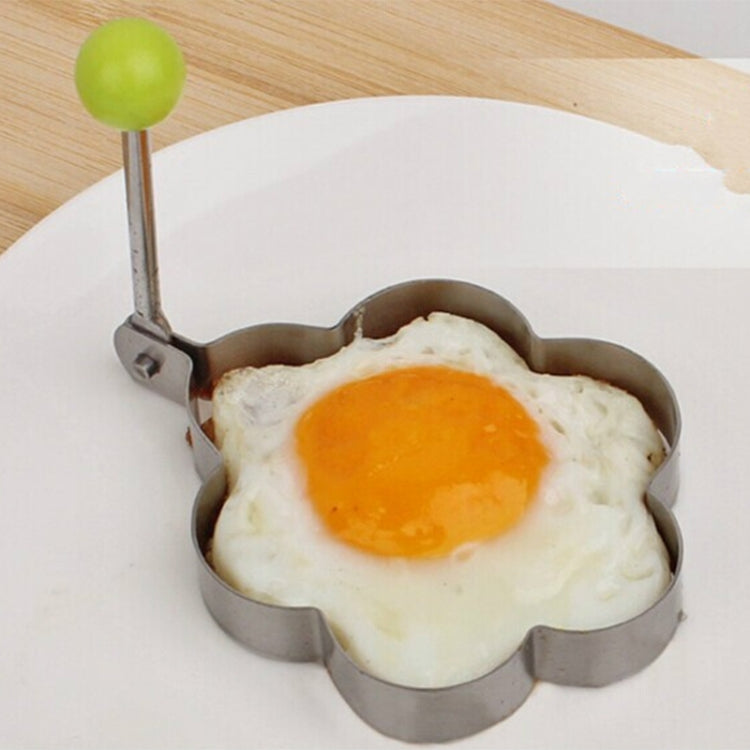 Plum-flower omelet mold with green knob handle, holding a fried egg.