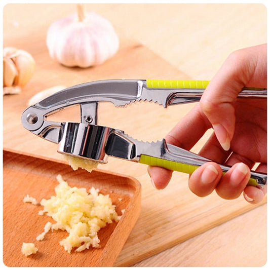 Stainless steel garlic press with minced garlic on a cutting board, green handles