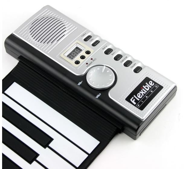 Soft keyboard piano control panel with speaker grille, knobs, and button row