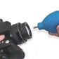 Air blower nozzle cleaning a black watch case head with blue rubber bulb