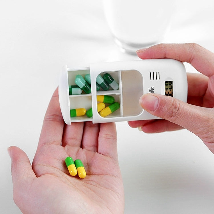 Smart pill reminder timer box in hands, showing green and yellow tablets