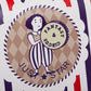 Circular sailor-girl badge close-up on striped long wallet with stars and checked background