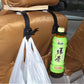 Two black plastic car seat hooks mounted on seatback, holding bag and bottle