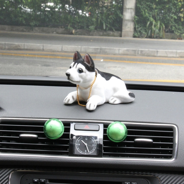 Black-and-white plush husky car decoration with gold chain, sitting on dashboard