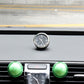 Round mini dashboard clock with black face and silver bezel mounted on a car dash