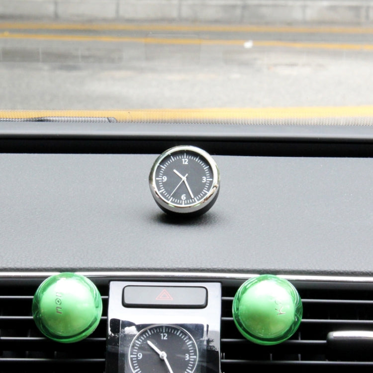 Round mini dashboard clock with black face and silver bezel mounted on a car dash