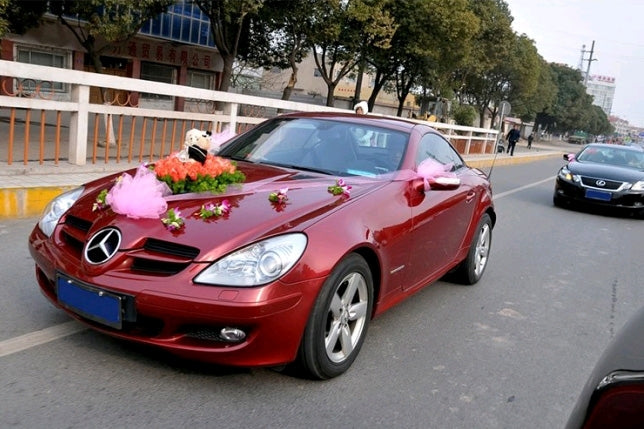 Double-sided adhesive tape used to secure decorative flower garland on a red car