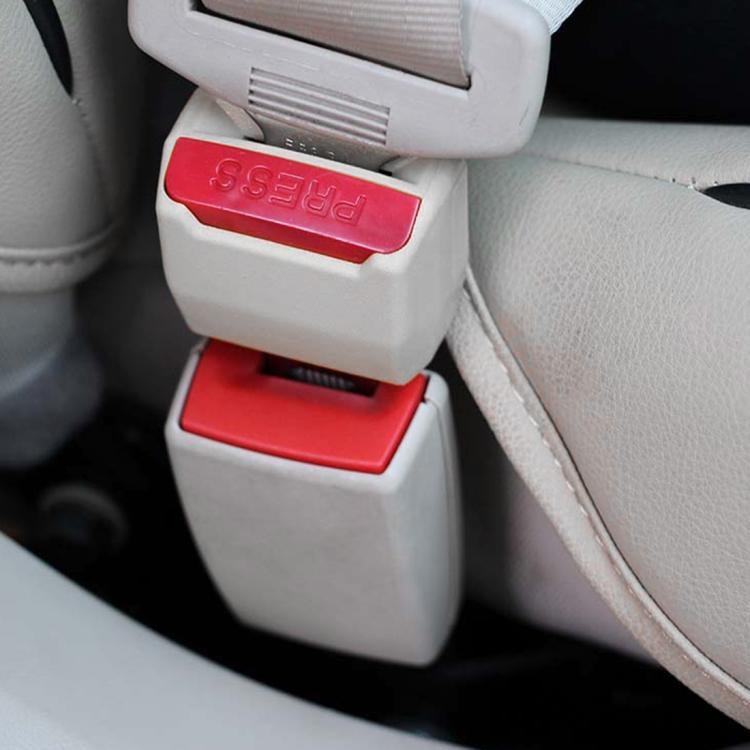 Car seat belt extension buckle with red PRESS button and black housing on seat