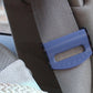 Blue car seat belt adjuster clamp fitted on a gray seat belt strap