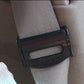Black car seat belt adjuster clamp fitted on a gray seat belt strap