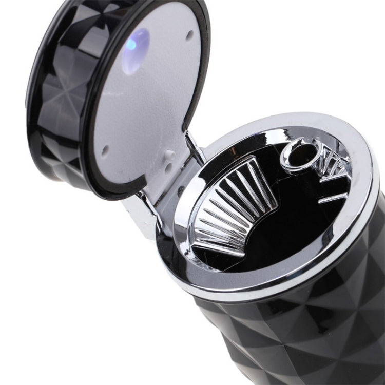 Close-up of open black diamond-pattern car ashtray with silver rim and LED light cover