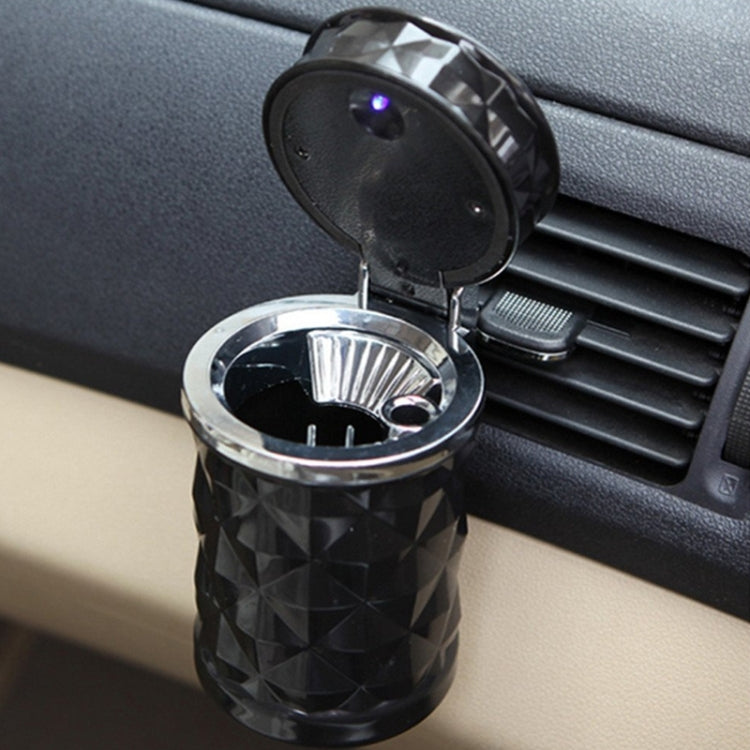Black diamond-pattern car ashtray with open lid, glowing blue LED, mounted near air vent