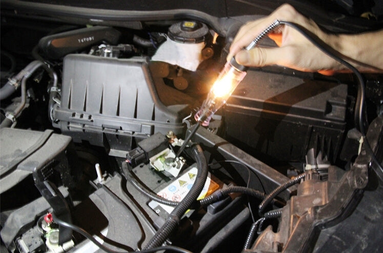 Hand using a circuit tester pen with probes on car engine wiring