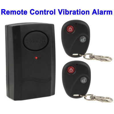 Black vibration alarm and two remote keyfobs with red and gray buttons on keyrings
