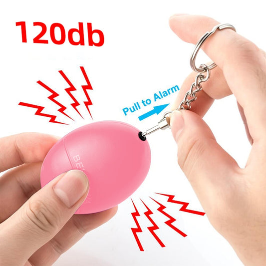 Pink oval personal alarm keychain with pull-pin, chain, and key ring in hand