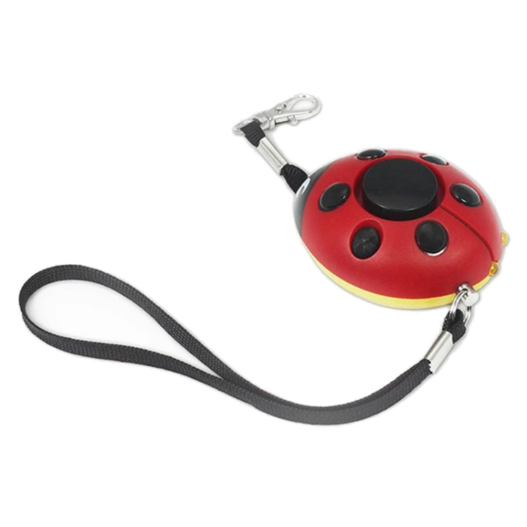 Red ladybug personal alarm with black spots, two metal clips, and long strap