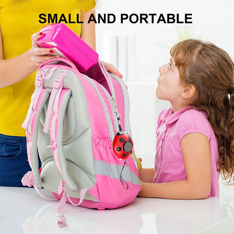 Red ladybug personal alarm clipped to a pink backpack strap for kids