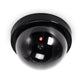 Dummy dome security camera, front view with glossy lens and glowing red LED