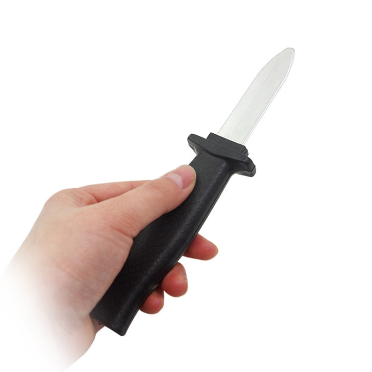 Retractable plastic gag knife held in hand, black handle with clear extended blade