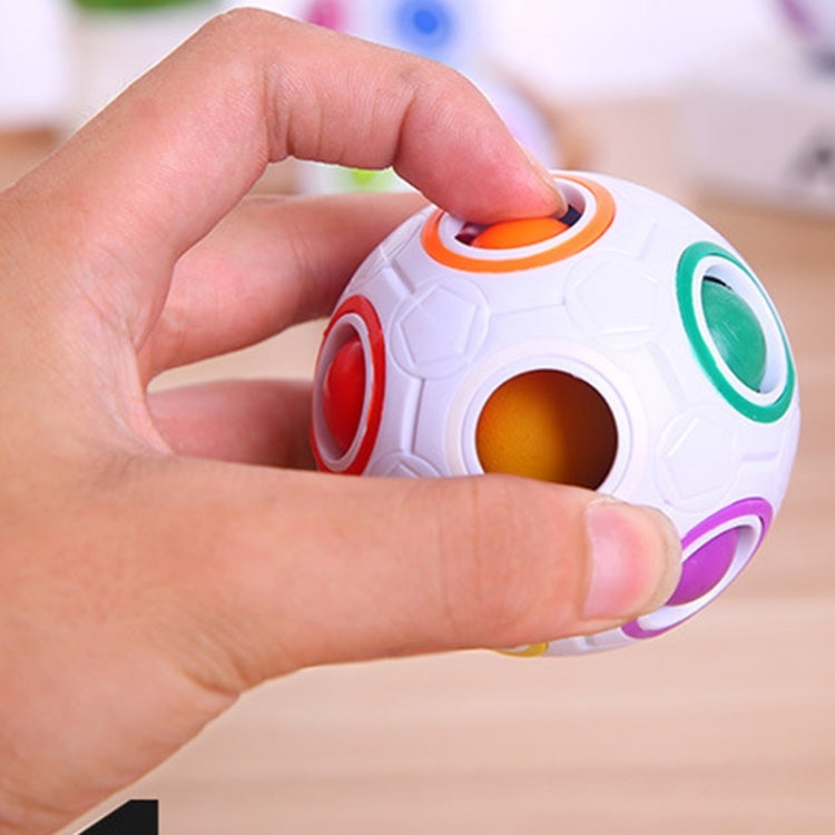 Hand holding white magic ball puzzle cube with orange ring and colored windows