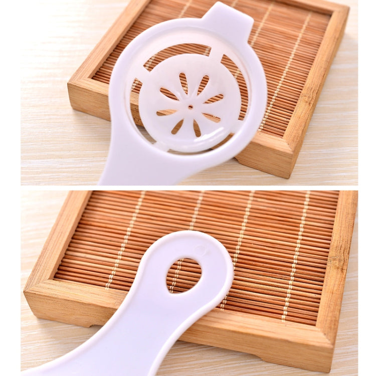 Egg separator, white scoop with vented disc insert shown on a wooden tray