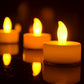 Close-up of glowing orange flameless LED tea light candles on a dark surface