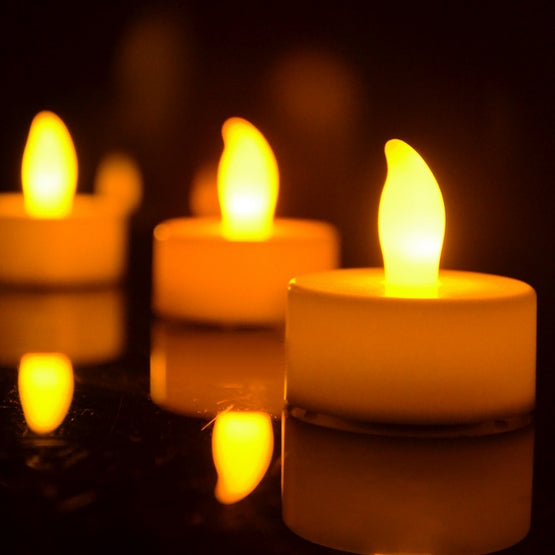 Close-up of glowing orange flameless LED tea light candles on a dark surface