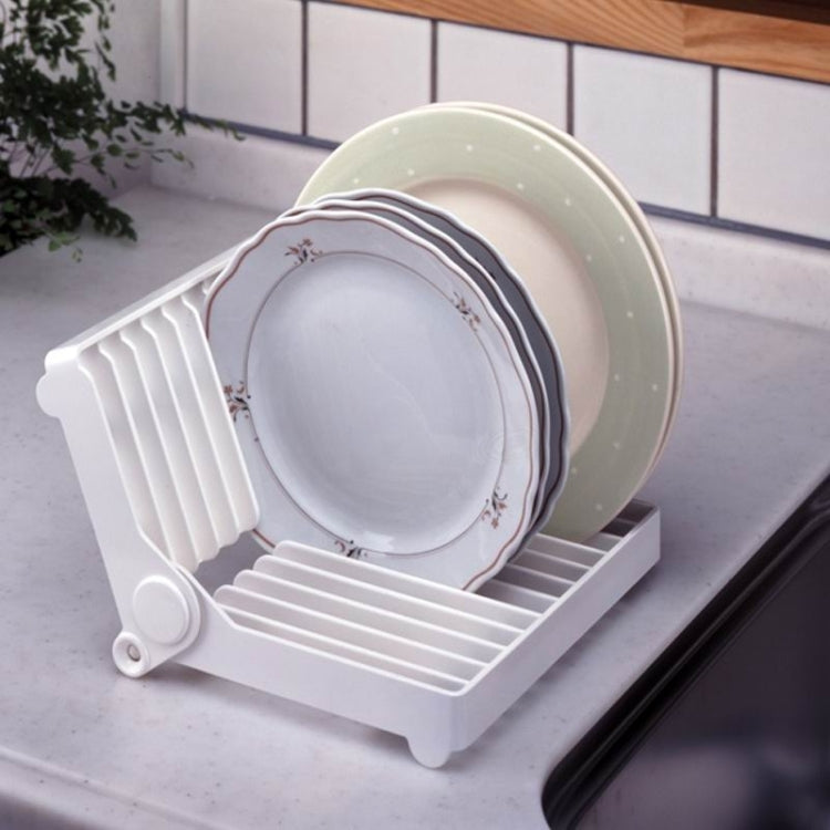 White foldable dish drip rack with plates resting on slotted tiers for drying