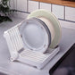 White foldable plate drying rack holding stacked plates and a pale green bowl