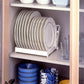 White plate drip rack installed in a cabinet, holding a vertical stack of plates