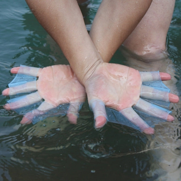 Silicone swim hand flippers on both hands, translucent light blue webbed fin pads in water