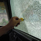 Yellow glass-break rescue tool used against car window by hand