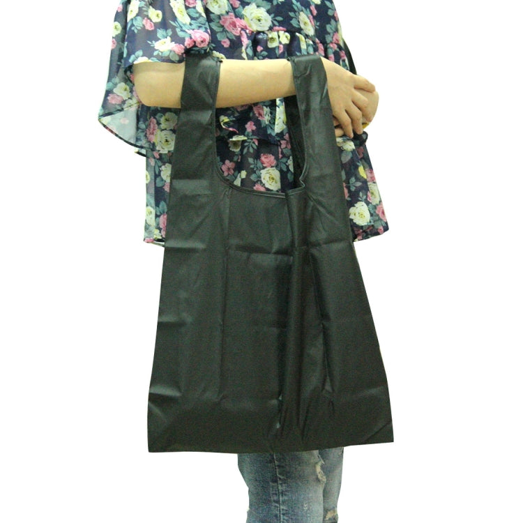 Dark green foldable nylon grocery tote bag with wide handles, held by person