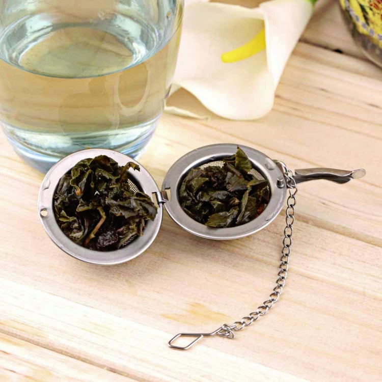 Large stainless steel tea infuser ball filled with dried tea leaves, with chain