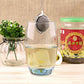 Large stainless steel mesh tea infuser ball hanging inside a glass mug