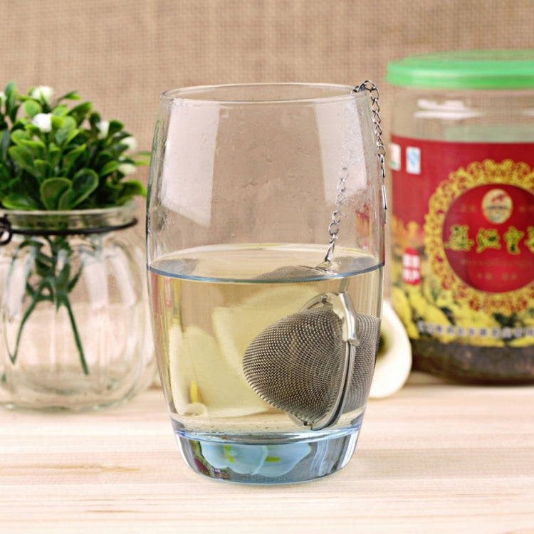 Large stainless steel mesh tea infuser ball steeping in a clear mug