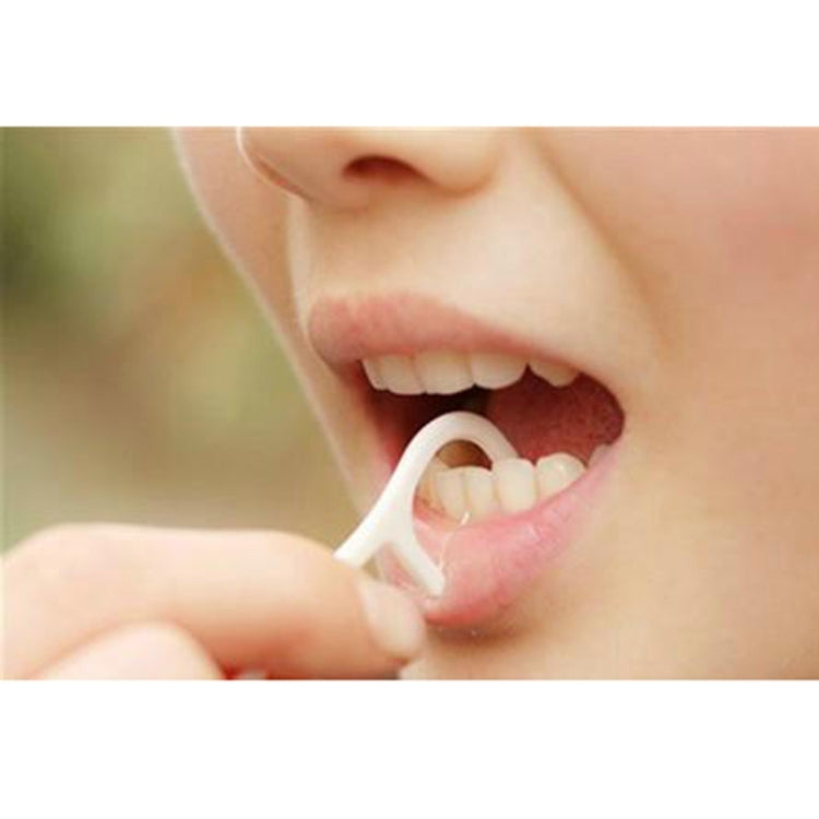 Hand holding a white flossing toothpick with looped thread, wide type