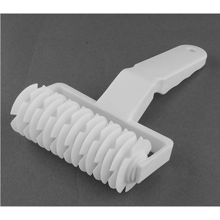 White plastic noodle cutter roller with evenly spaced comb teeth and handle