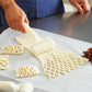 White plastic noodle netting cutter rolling lattice on dough sheet