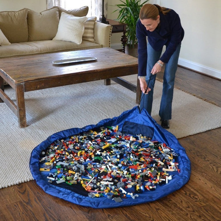Round blue kids toy storage bag with toy pieces inside on a living room floor