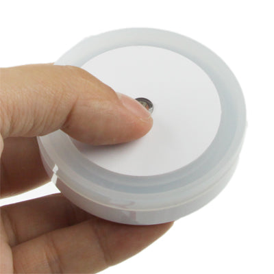 White LED night light with round button, shown being pressed by hand