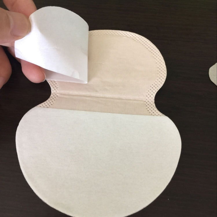 Adhesive underarm pad held in hand, showing backing layer, white