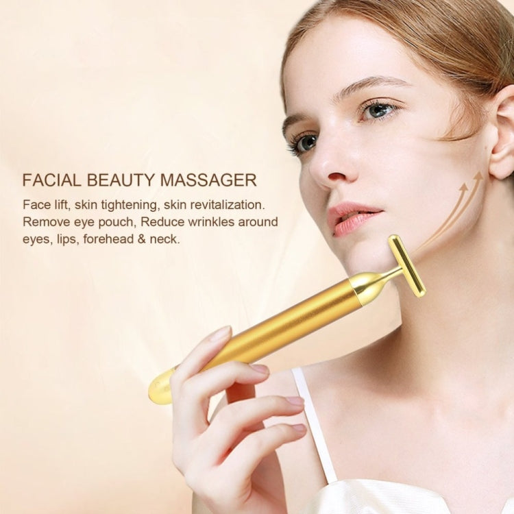 Gold electric face massage stick with U-shaped roller head held at the cheek