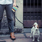 Retractable dog leash with multicolor striped handle pouch held for a walk