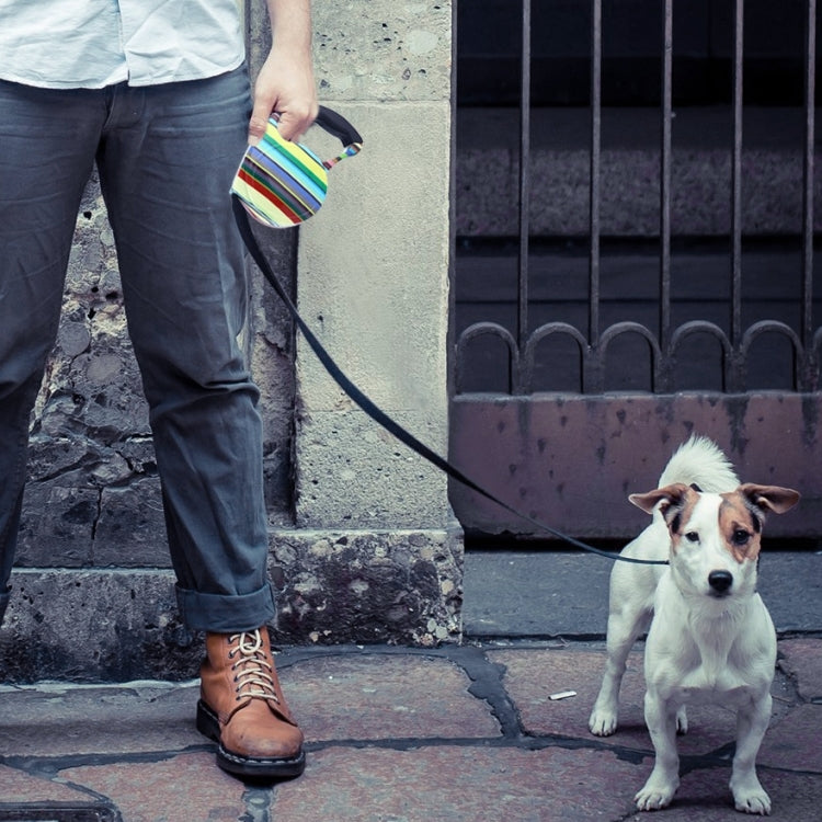 Retractable dog leash with multicolor striped handle pouch held for a walk